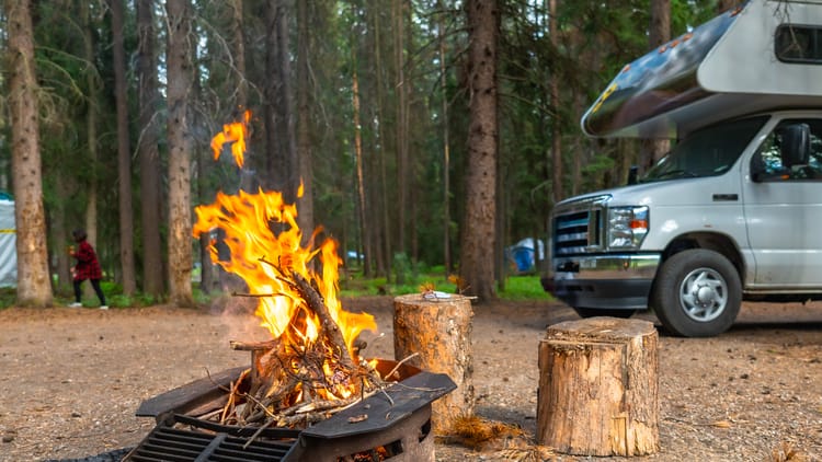 campfire-burning-brightly-next-to-rv-in-campsite